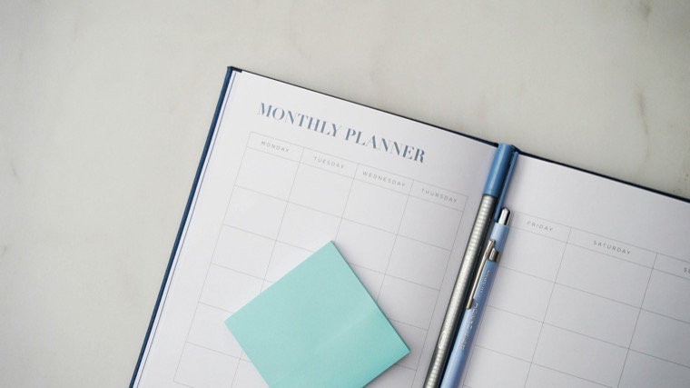 An open monthly planner with a pen