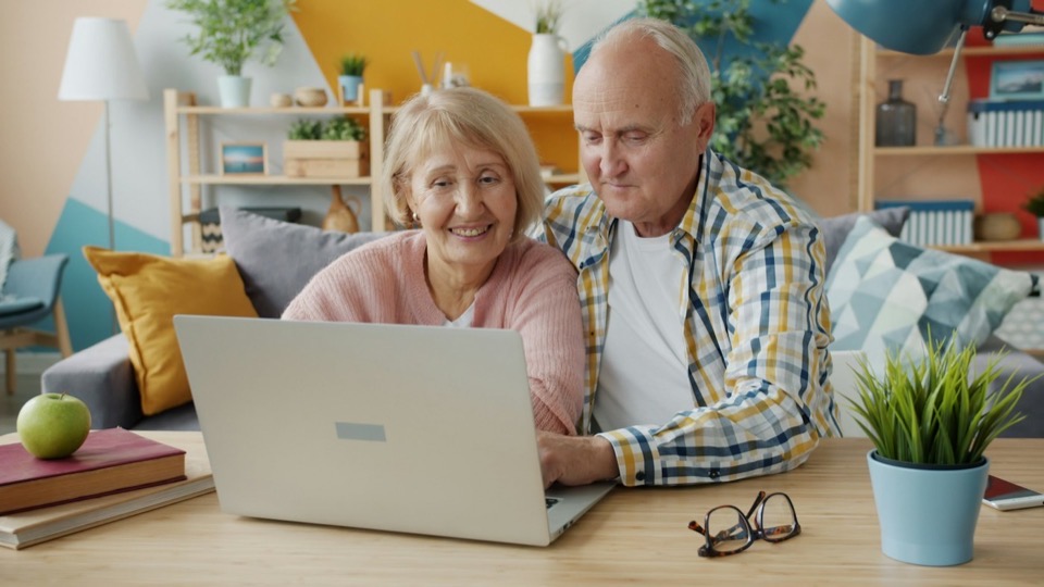 An older couple looking at a laptop together on the sofa