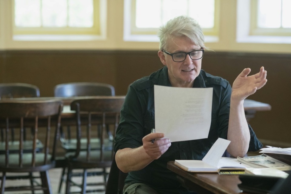 An older man reading a letter at a table